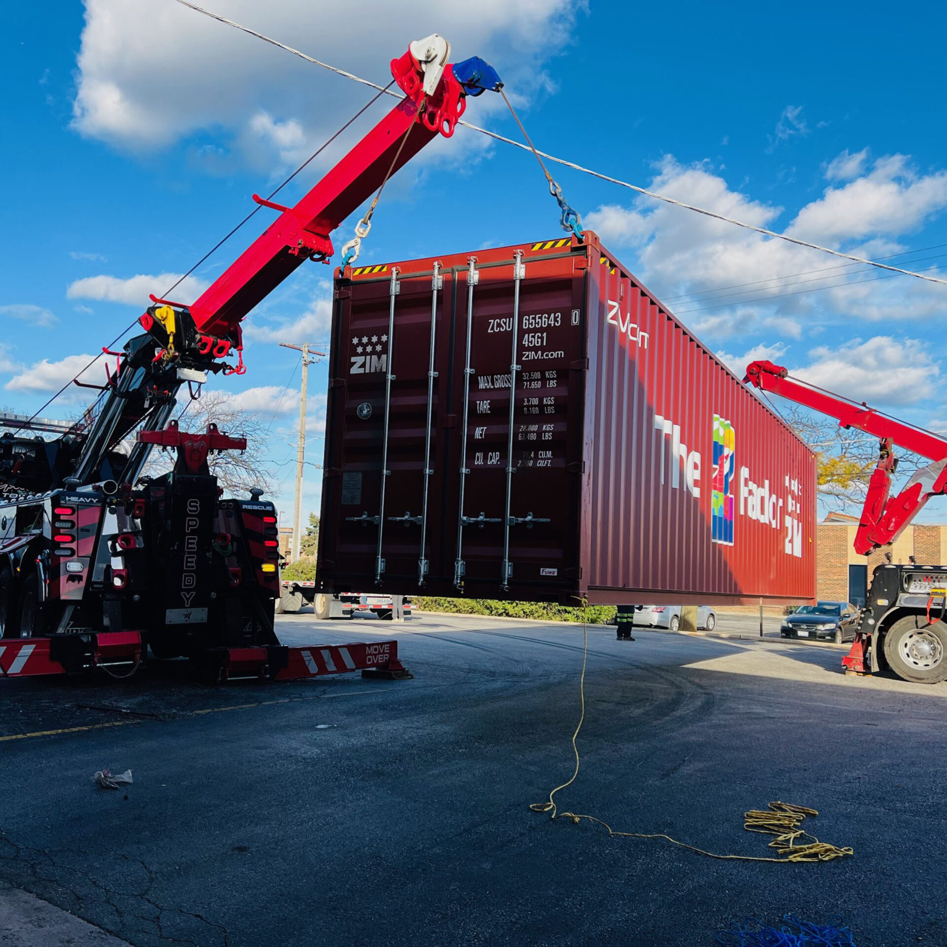 Two Speedy G trucks lifting a shipping container off the ground