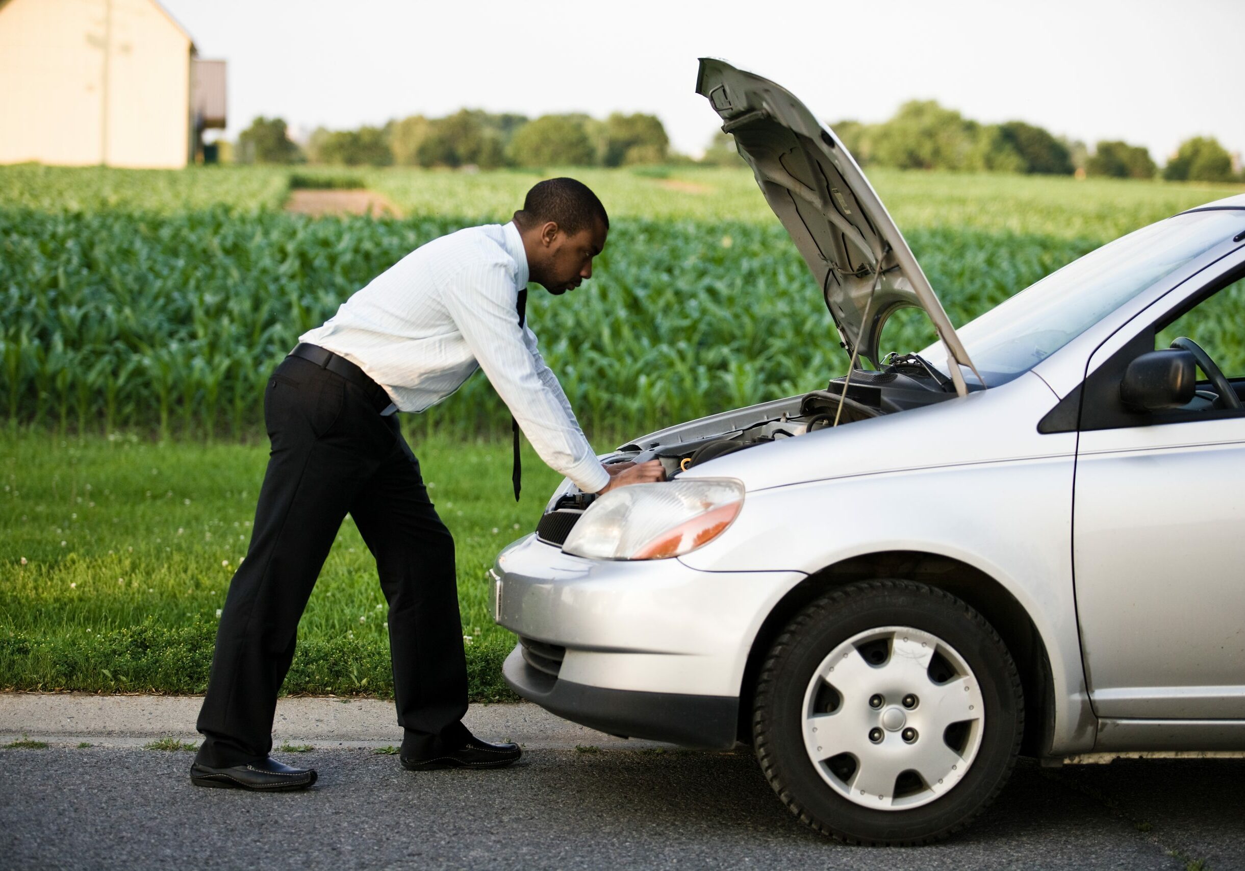 businessman-looking-under-hood-of-car-at-rural-roadside-breakdown-1881333-scaled